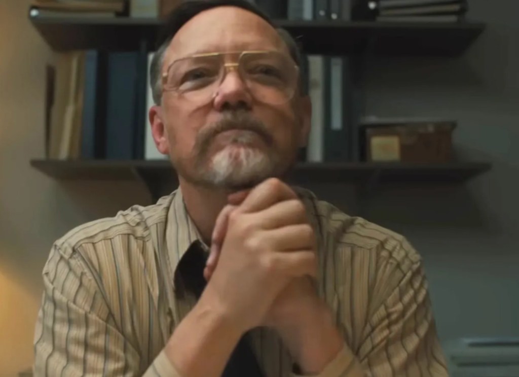 William Afton in Five Nights at Freddy's (2023) appearing composed and professional in an office setting, contrasting with his concealed violent actions.